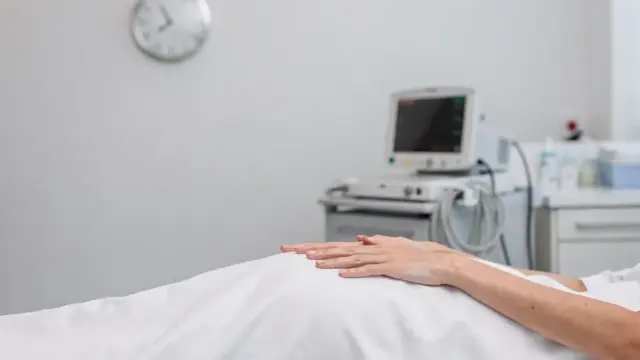 Klinisches Foto zu Geburtszeichen erkennen: Schwangere Hände in einer Geburtsstation mit Monitor und Bett