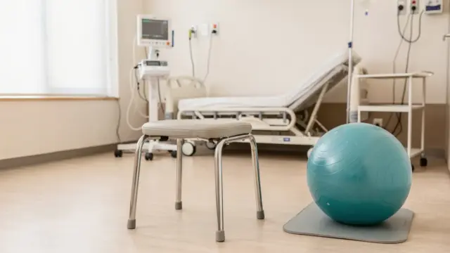 Aufrechte Geburt mit Geburtsstuhl und Gymnastikball in einem hellen Kreißsaal