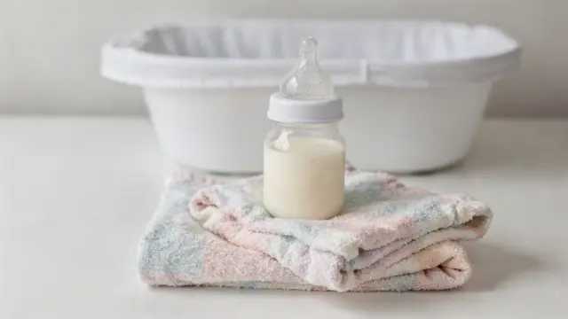 Babyfüße neben Flasche und Decke: Bild zu Hungerzeichen beim Baby erkennen